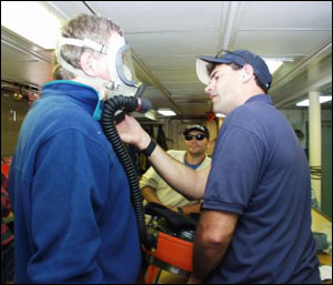 Researcher Steve Hurst being fitted for the Alvin emergency oxygen mask by Alvin pilot Bruce Strictrott. Photo by Monte Basgall. Nicholas School of the Environment, Duke University.